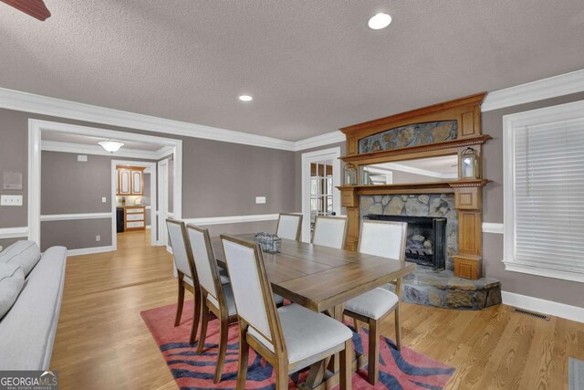 dining room with crown molding, a textured ceiling, and light wood-type flooring