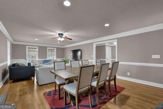 dining room featuring crown molding, hardwood / wood-style floors, ceiling fan, and a textured ceiling