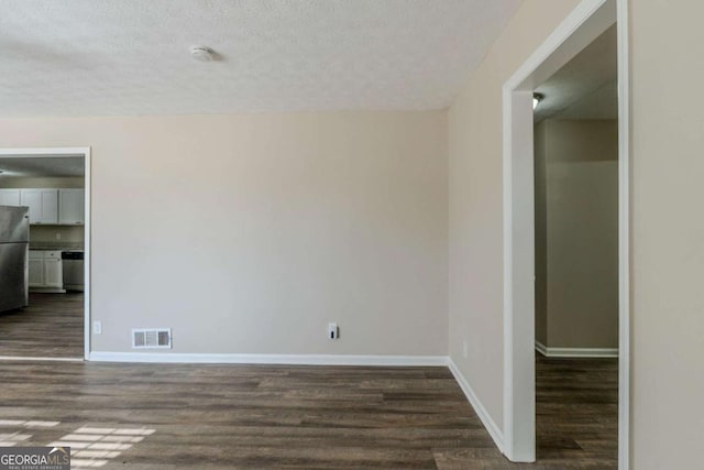 empty room with dark wood-type flooring and a textured ceiling