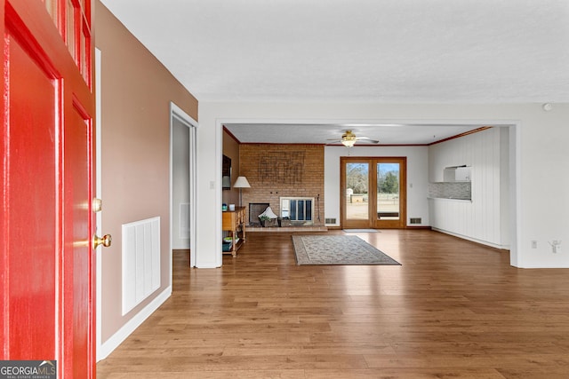 interior space featuring hardwood / wood-style floors, a fireplace, french doors, and ceiling fan