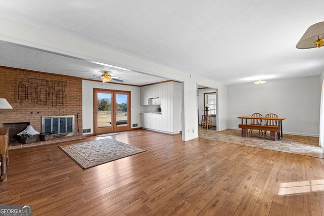 living room with hardwood / wood-style floors, a textured ceiling, french doors, and a brick fireplace