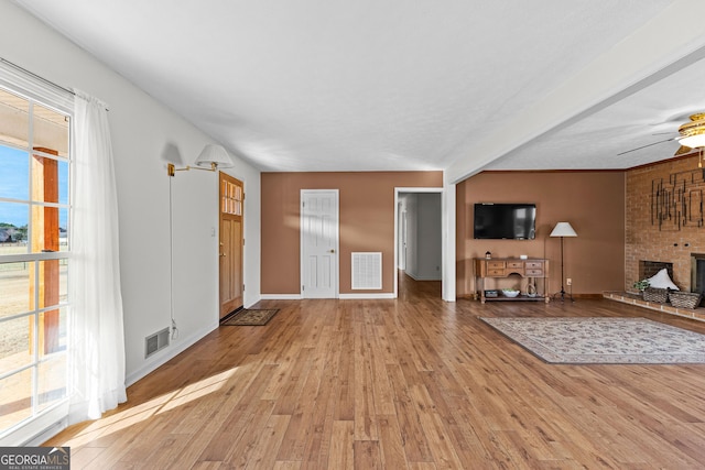 unfurnished living room featuring a fireplace, ceiling fan, and light wood-type flooring