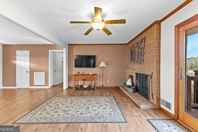 living room featuring a fireplace, wood-type flooring, ornamental molding, and ceiling fan