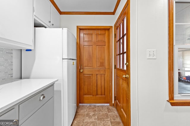 kitchen with crown molding, white cabinets, and white fridge