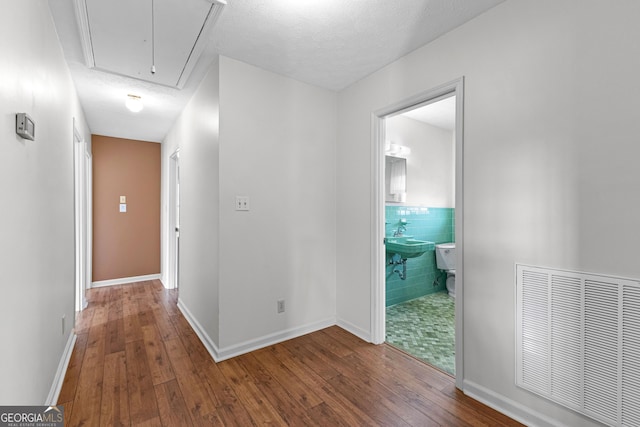 corridor with sink, wood-type flooring, and a textured ceiling