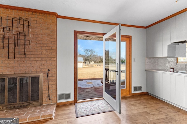 doorway with ornamental molding and light wood-type flooring