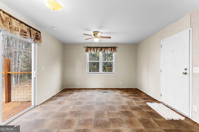 empty room with ceiling fan and a textured ceiling