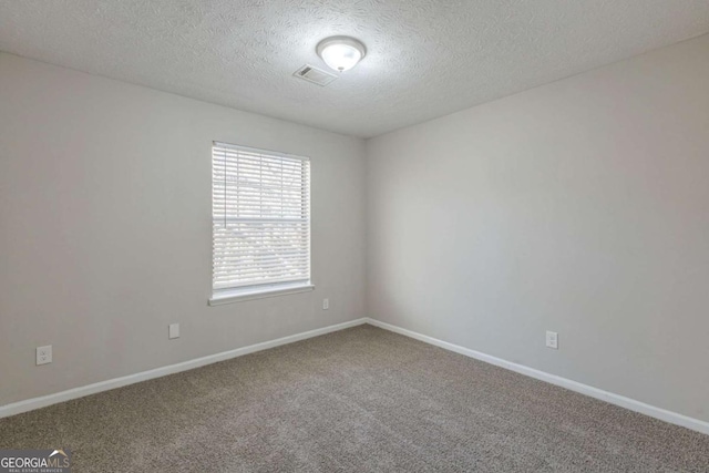 carpeted empty room featuring a textured ceiling