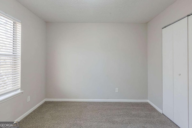 unfurnished bedroom with carpet, a textured ceiling, and a closet