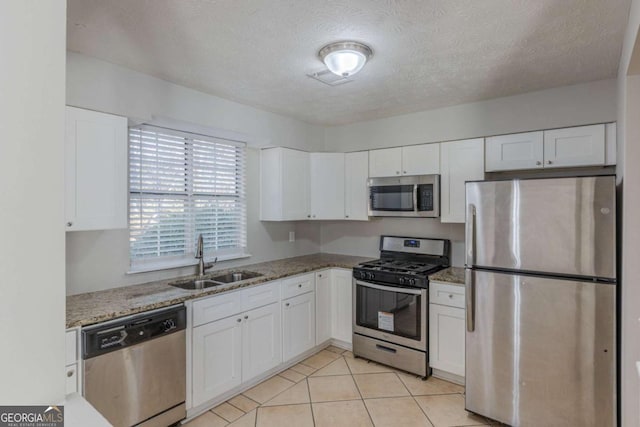 kitchen with white cabinetry, appliances with stainless steel finishes, sink, and light stone counters