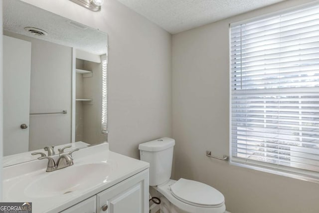 bathroom featuring plenty of natural light, toilet, vanity, and a textured ceiling