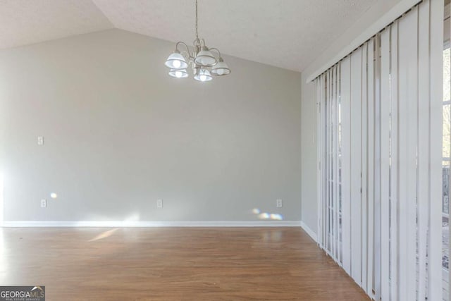 unfurnished room with vaulted ceiling, hardwood / wood-style floors, and a notable chandelier