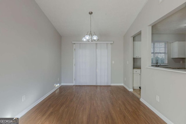 unfurnished dining area with sink, hardwood / wood-style floors, a textured ceiling, and an inviting chandelier