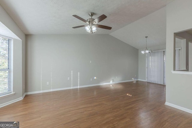 unfurnished living room with lofted ceiling, hardwood / wood-style flooring, ceiling fan with notable chandelier, and a textured ceiling