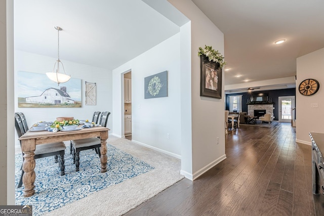 dining space featuring a stone fireplace and dark hardwood / wood-style flooring