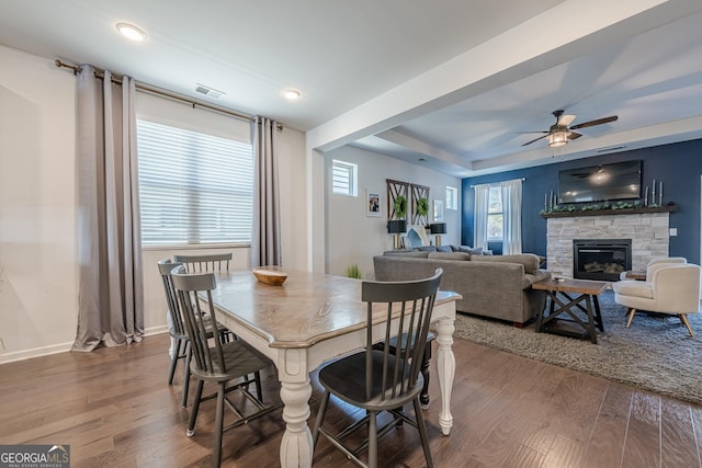 dining room featuring ceiling fan, hardwood / wood-style floors, a fireplace, and a tray ceiling