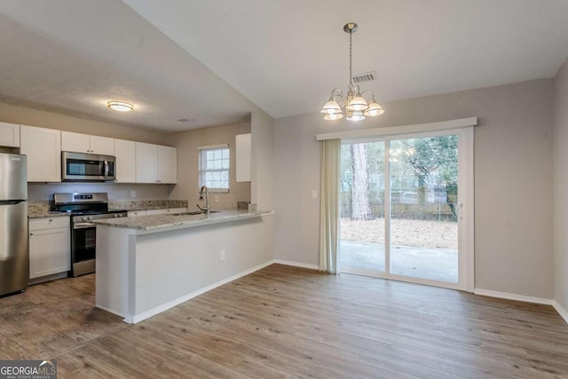 kitchen featuring hanging light fixtures, stainless steel appliances, kitchen peninsula, and white cabinets