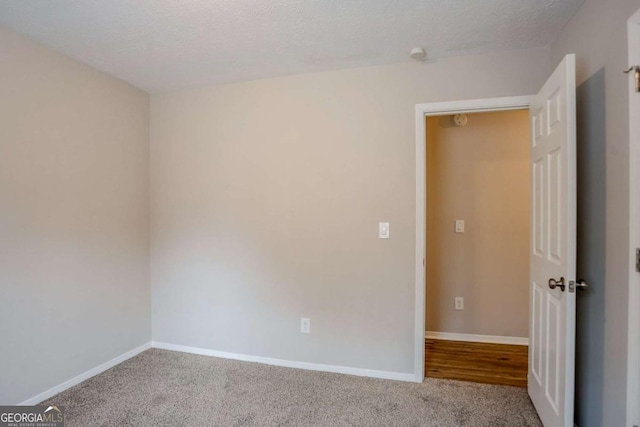 unfurnished room featuring a textured ceiling and carpet