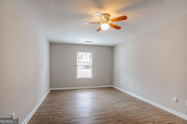 empty room featuring ceiling fan, a textured ceiling, and light wood-type flooring