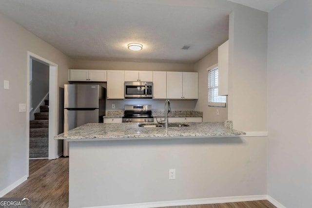 kitchen featuring appliances with stainless steel finishes, sink, white cabinets, and kitchen peninsula