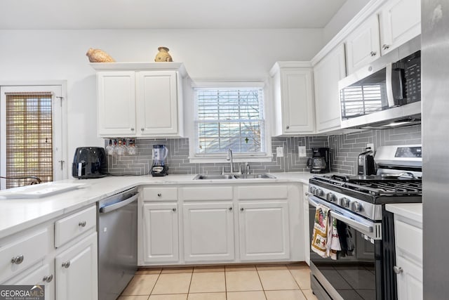 kitchen featuring sink, white cabinetry, tasteful backsplash, light tile patterned floors, and stainless steel appliances