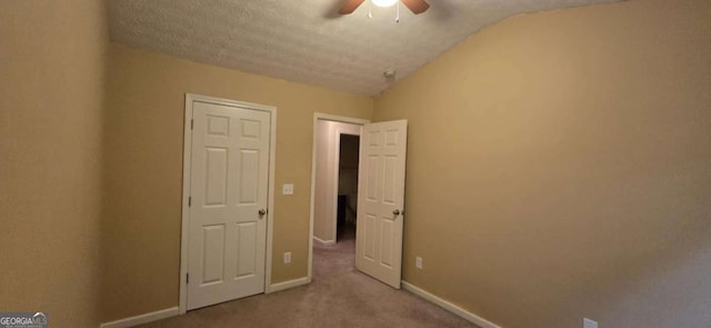 unfurnished bedroom featuring ceiling fan, lofted ceiling, light carpet, and a textured ceiling