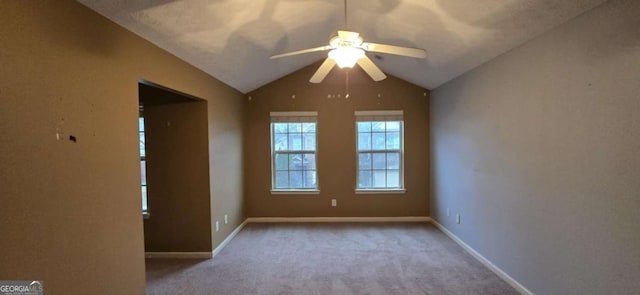 empty room with ceiling fan, lofted ceiling, and light colored carpet