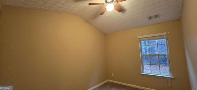 carpeted empty room with ceiling fan, vaulted ceiling, and a textured ceiling