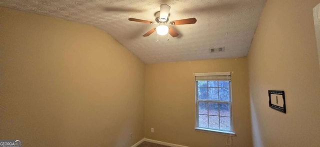 spare room with vaulted ceiling, a wealth of natural light, ceiling fan, and a textured ceiling