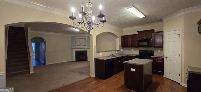 kitchen with sink, hanging light fixtures, ornamental molding, a center island, and black appliances