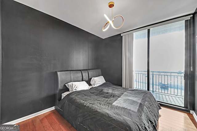 bedroom featuring a water view, wood-type flooring, access to exterior, and floor to ceiling windows