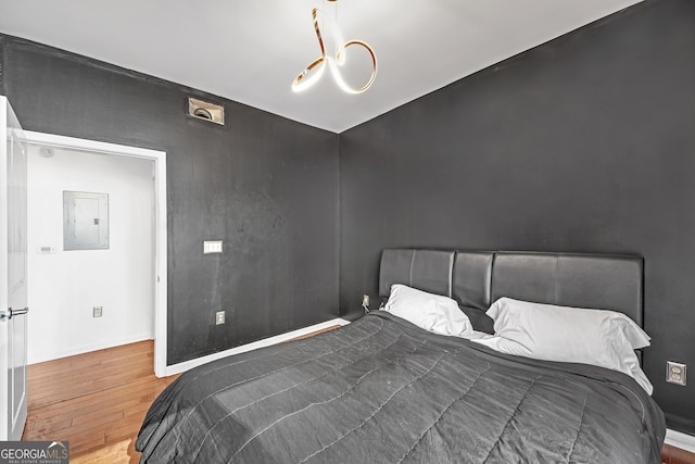 bedroom with electric panel and hardwood / wood-style floors