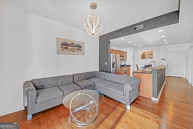 living room featuring sink, a chandelier, and light hardwood / wood-style floors