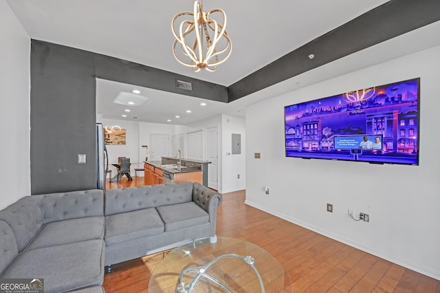 living room with sink, a notable chandelier, and light wood-type flooring