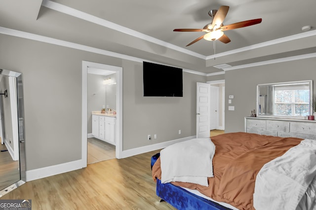 bedroom featuring ceiling fan, ornamental molding, a tray ceiling, and ensuite bath