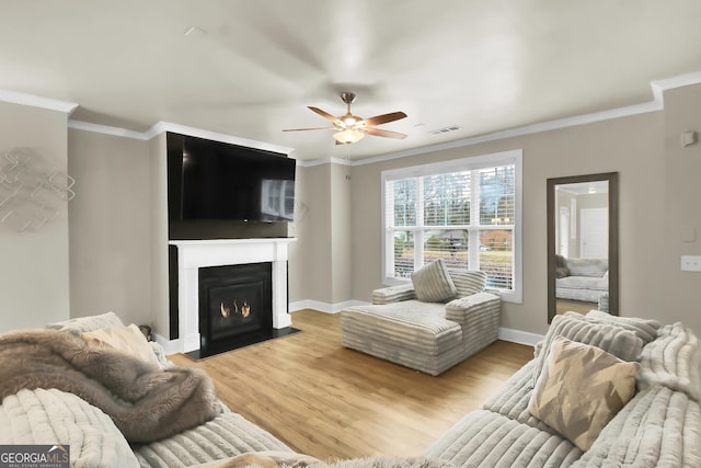 living room with ornamental molding, ceiling fan, and light hardwood / wood-style floors