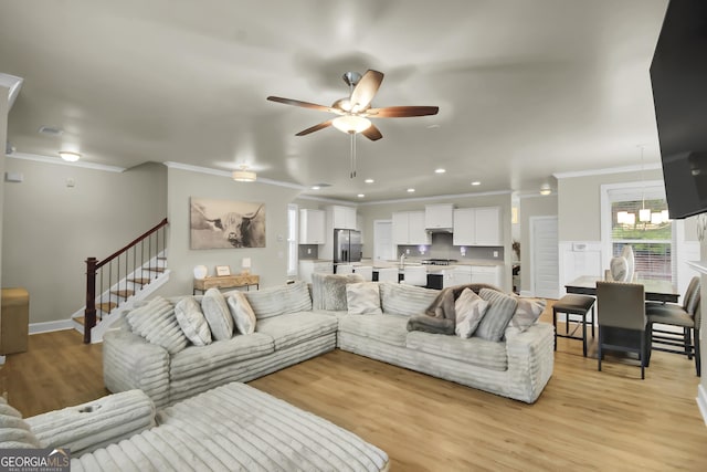 living room featuring crown molding, light hardwood / wood-style flooring, and ceiling fan with notable chandelier