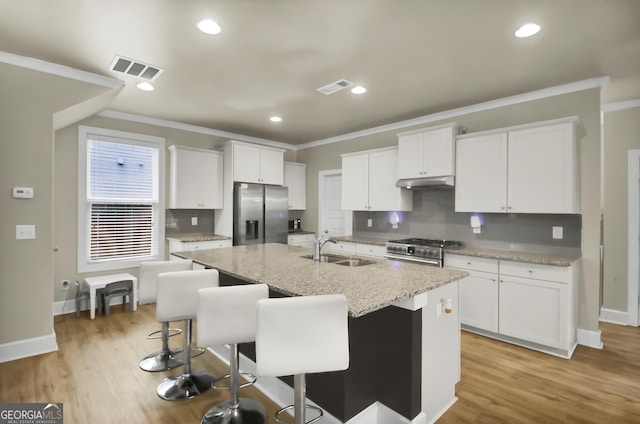 kitchen with sink, white cabinetry, a center island with sink, stainless steel appliances, and a kitchen bar