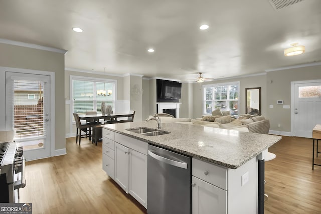 kitchen featuring appliances with stainless steel finishes, a wealth of natural light, an island with sink, sink, and white cabinets