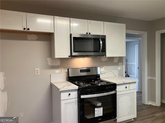 kitchen with stainless steel appliances, light stone countertops, dark wood-type flooring, and white cabinets