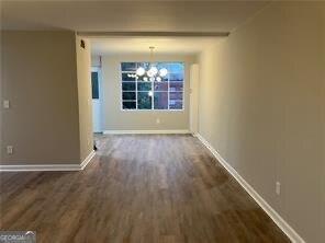 unfurnished dining area with an inviting chandelier and dark wood-type flooring