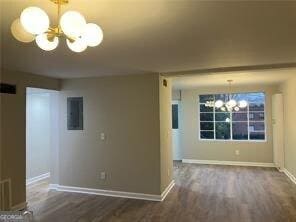 unfurnished living room with a notable chandelier, electric panel, and dark hardwood / wood-style floors