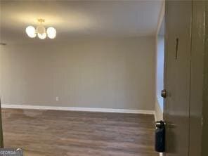 empty room featuring dark wood-type flooring and a chandelier