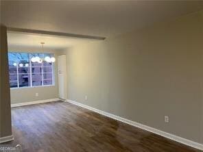 unfurnished room featuring dark hardwood / wood-style flooring and a chandelier