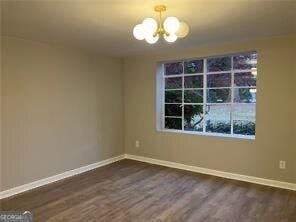 empty room featuring dark hardwood / wood-style flooring and an inviting chandelier