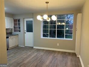 unfurnished dining area featuring dark wood-type flooring and a chandelier