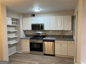 kitchen with white cabinetry, appliances with stainless steel finishes, sink, and hardwood / wood-style floors