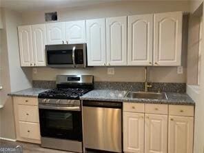 kitchen featuring sink, stainless steel appliances, and white cabinets