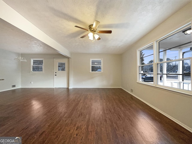 spare room with ceiling fan with notable chandelier, dark hardwood / wood-style floors, and a textured ceiling