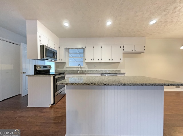 kitchen featuring a kitchen island, appliances with stainless steel finishes, dark hardwood / wood-style floors, white cabinetry, and a textured ceiling